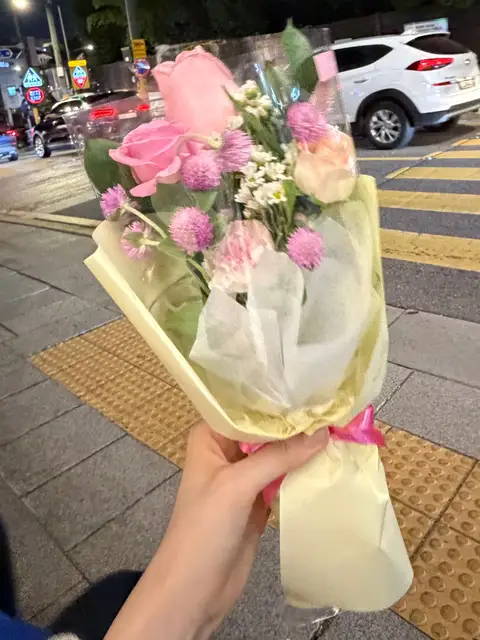 밤 거리에서 꽃다발을 들고 있는 손
